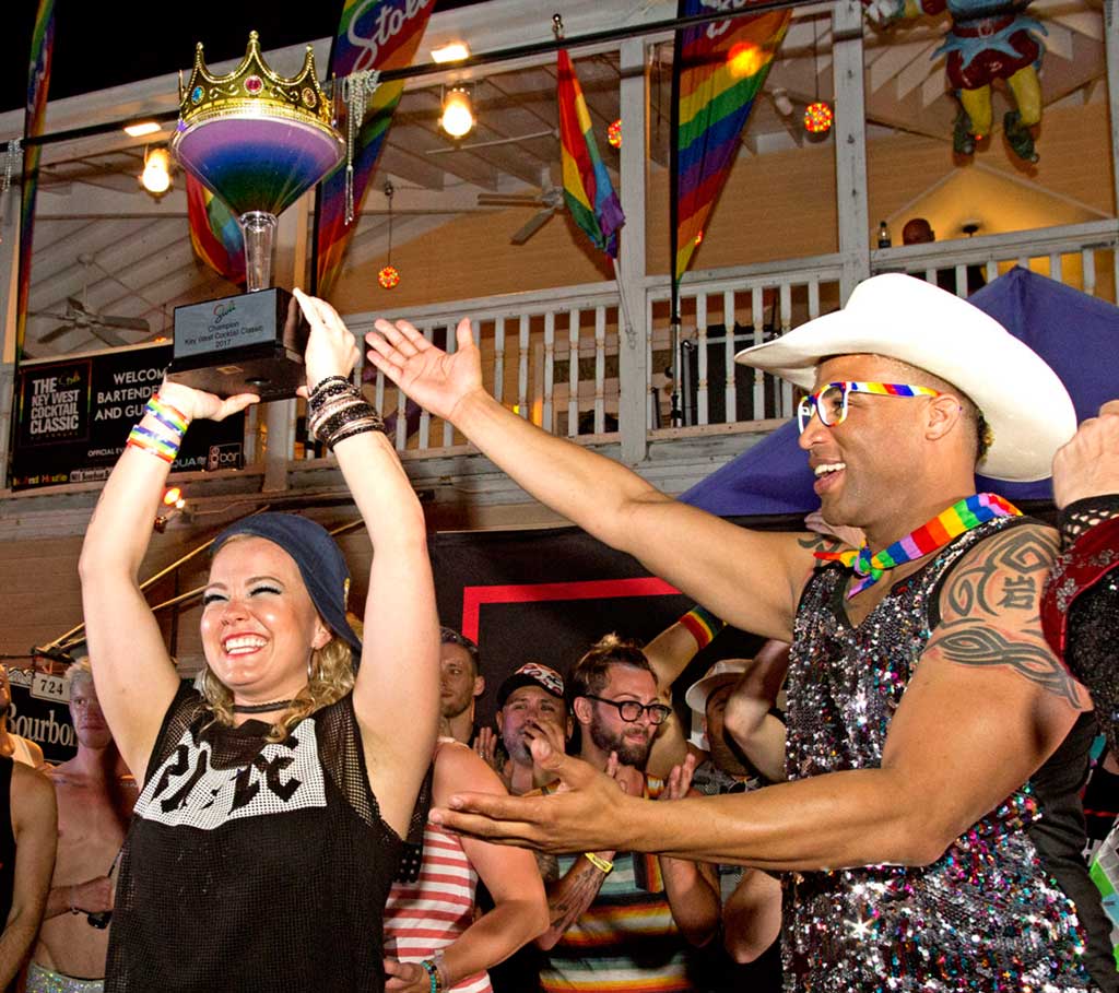 Kayla Hasbrook, left, hoists the Stoli Key West Cocktail Classic championship trophy Saturday, June 10, 2017, in Key West, Fla. Hasbrook, a New York City bartender, concocted a libation entitled “No Sleep Till Sunrise” to garner top honors among winners of 17 North American regional competitions. At right is 2016 winner Rocky Collins of Dallas. photo Credit: Carol Tedesco/Florida Keys News Bureau
